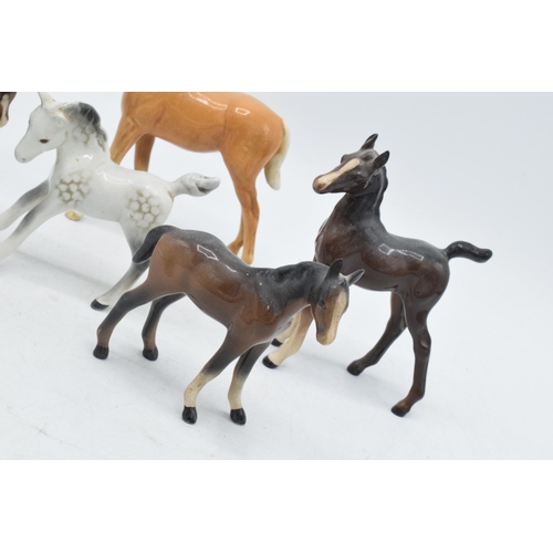 60H - A collection of Beswick foals to include a palomino example, a grey foal and 3 in brown colourways i... 