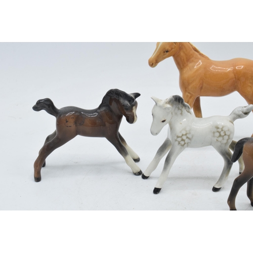 60H - A collection of Beswick foals to include a palomino example, a grey foal and 3 in brown colourways i... 