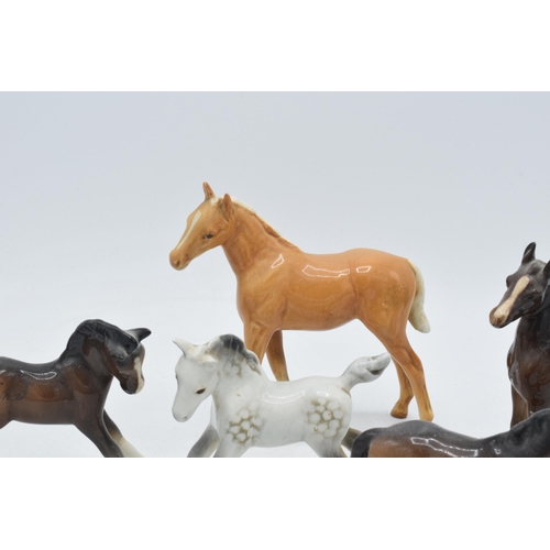 60H - A collection of Beswick foals to include a palomino example, a grey foal and 3 in brown colourways i... 