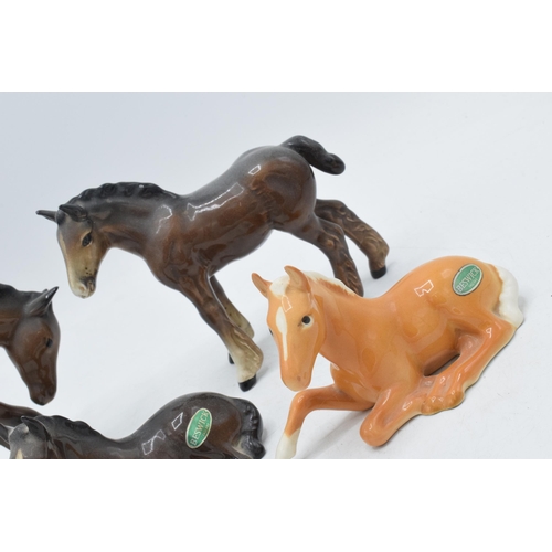 60J - Beswick to include 1053 brown foal, 915 lying foal in brown and palomino and a head tucked foal (4).