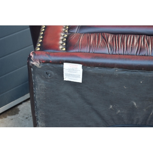 404 - Red oxblood leather Chesterfield-style button-back armchair with metal beading, 110x96x92cm tall.