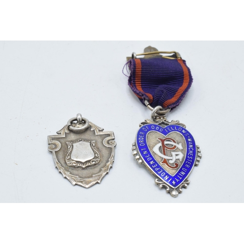 180G - A silver enamelled Oddfellows of Manchester fob together with a silver shield fob (2).