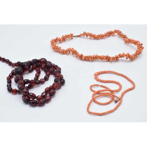 180O - A pair of coral bead necklaces, both with 9ct gold clasps, together with a string of faceted bakelit... 