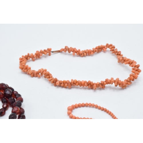 180O - A pair of coral bead necklaces, both with 9ct gold clasps, together with a string of faceted bakelit... 