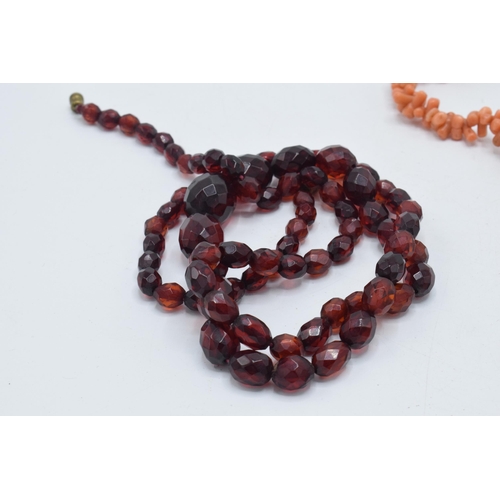 180O - A pair of coral bead necklaces, both with 9ct gold clasps, together with a string of faceted bakelit... 