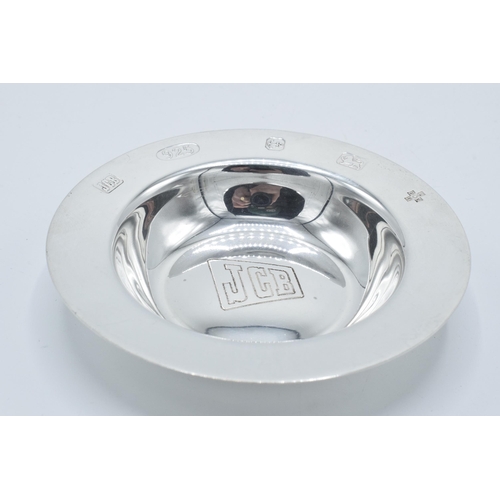 111 - Silver pin dish / ash tray engraved with 'JCB' logo, 64.0 grams, Birmingham 2000, 10cm diameter.