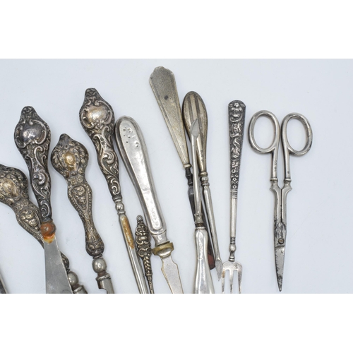 113 - A good collection of silver-handled items to include scissors, knives, button hooks etc (Qty).