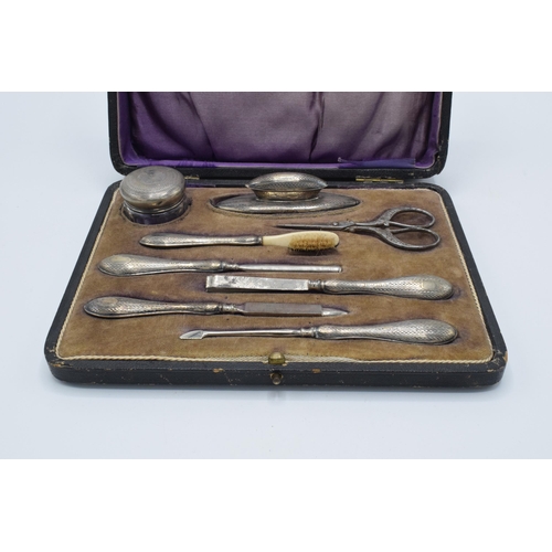 122 - Silver handled manicure set with 8 pieces to include a nail buffer, lidded jar, nail file and others... 