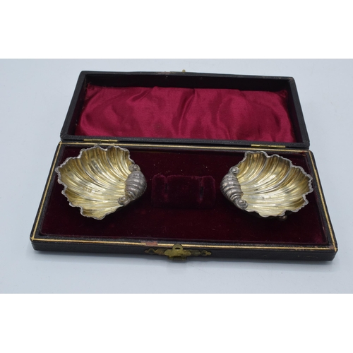 209 - A cased pair of silver shell salt dishes in velvet and fabric lined case, 15.0 grams.