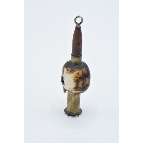 248 - Vintage Trench Art of a carved bone in the form of a skull with an ammunition shell, 9cm tall, mount... 