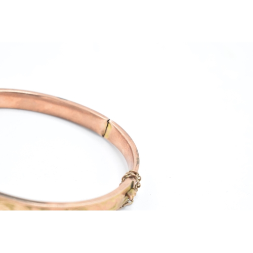 318 - 9ct rose gold bangle with engraved decoration, 8.8 grams, split to rear, 65mm diameter.