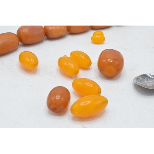 336 - A collection of butterscotch amber (or similar) items to include raw block, a graduated necklace and... 