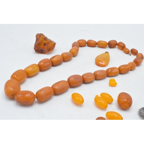 336 - A collection of butterscotch amber (or similar) items to include raw block, a graduated necklace and... 