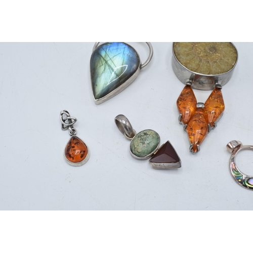 383 - An interesting collection of silver pendants with various gemstones and similar materials of varying... 