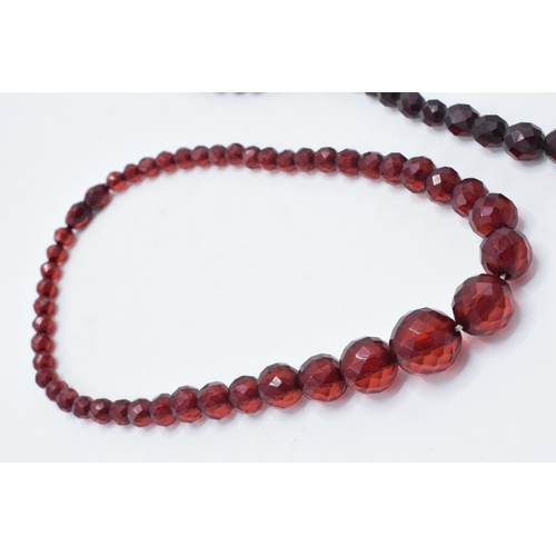 387 - A pair of vintage bakelite cherry amber (or similar) graduated necklaces with faceted beads, each ap... 