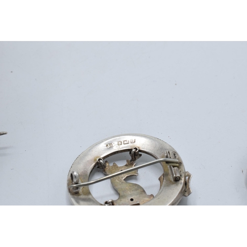 399 - A large silver 830s Scandinavian brooch with traditional scenes together with a Scottish deer brooch... 