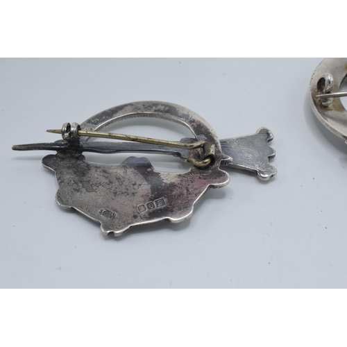 399 - A large silver 830s Scandinavian brooch with traditional scenes together with a Scottish deer brooch... 