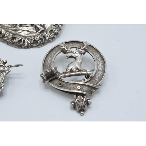 399 - A large silver 830s Scandinavian brooch with traditional scenes together with a Scottish deer brooch... 