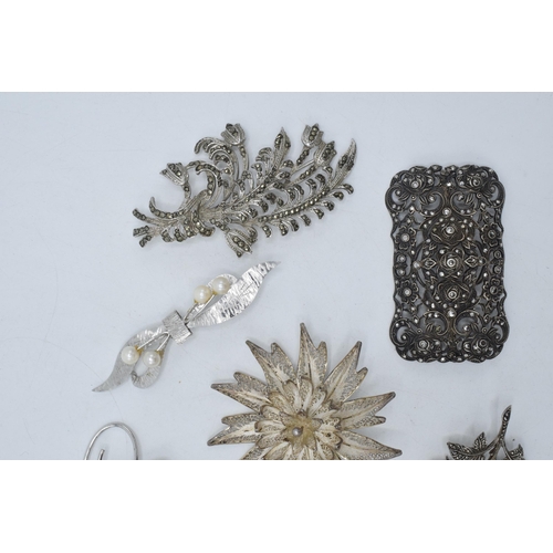 401 - A collection of silver brooches to mainly consist of floral designs to include marcasite and filigre... 