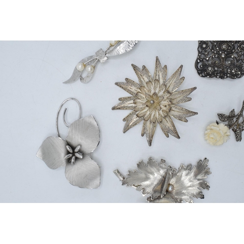 401 - A collection of silver brooches to mainly consist of floral designs to include marcasite and filigre... 