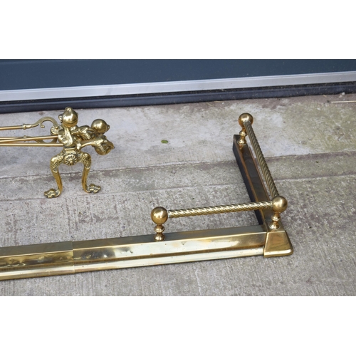 498 - A pair of antique brass fireside dogs along with a companion set and a brass and metal fender.