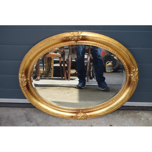 507 - Reproduction oval gilt mirror with bevel edged mirror, 86x66cm.