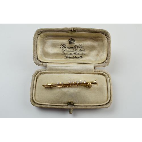 397 - 9ct gold diamond set bar brooch in the form of a clarinet, 2.5 grams, 4.5cm wide.