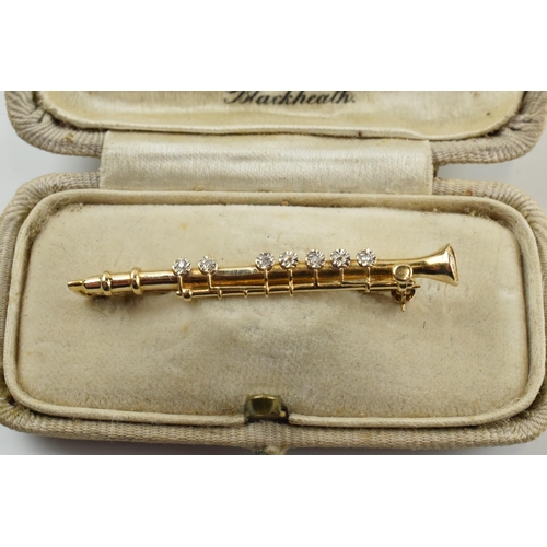 397 - 9ct gold diamond set bar brooch in the form of a clarinet, 2.5 grams, 4.5cm wide.