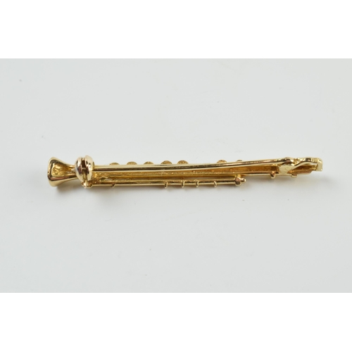 397 - 9ct gold diamond set bar brooch in the form of a clarinet, 2.5 grams, 4.5cm wide.