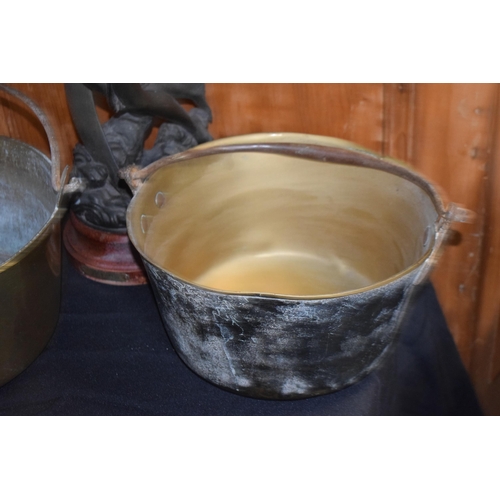 301 - A pair of antique brass jam pans with heavy duty handles, together with a spelter figure of wood eff... 