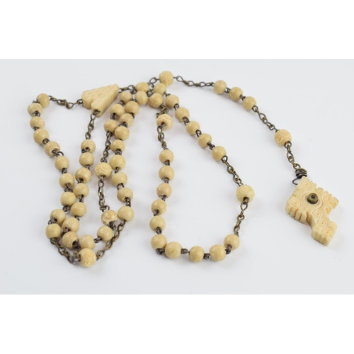 405I - A set of bone rosary beads with cross stanhope with village scenes, 52cm long.