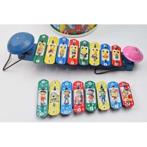 418 - A trio of vintage childrens toys to include a pair of metal xylophones and a drum decorated with clo... 