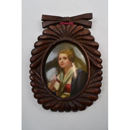 81D - Oval painted ceramic portrait of a girl holding a flower in wooden frame, plaque 8cm long.