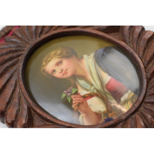 81D - Oval painted ceramic portrait of a girl holding a flower in wooden frame, plaque 8cm long.