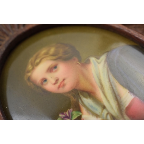 81D - Oval painted ceramic portrait of a girl holding a flower in wooden frame, plaque 8cm long.