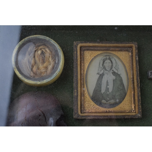 197 - Framed Memento Mori containing lock of hair, carved wooden skull, crucifix, and plaque that reads 