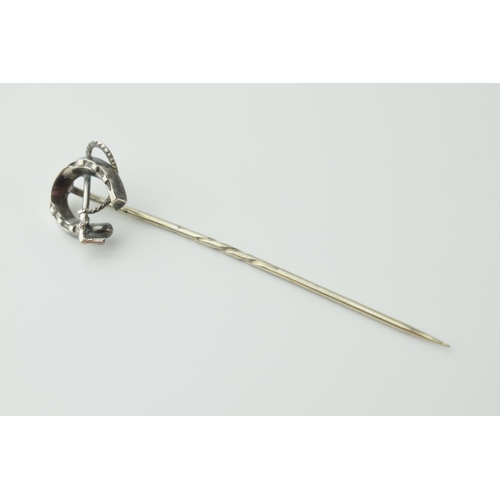 566 - White metal horseshoe stick pin with riding crop, 6.5cm long.