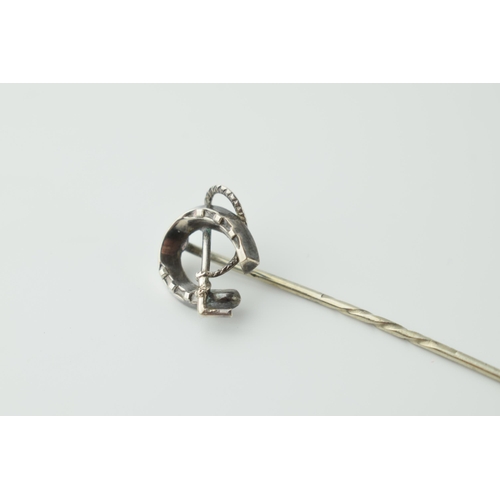 566 - White metal horseshoe stick pin with riding crop, 6.5cm long.