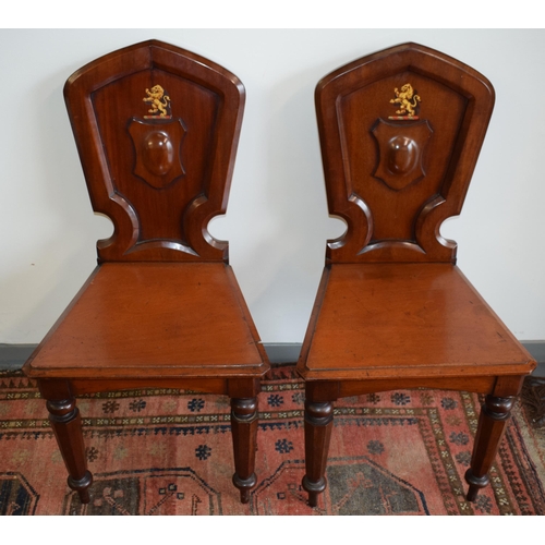 217 - A pair of antique mahogany hall chairs with lion emblem and shaped backs, 92cm tall (2).