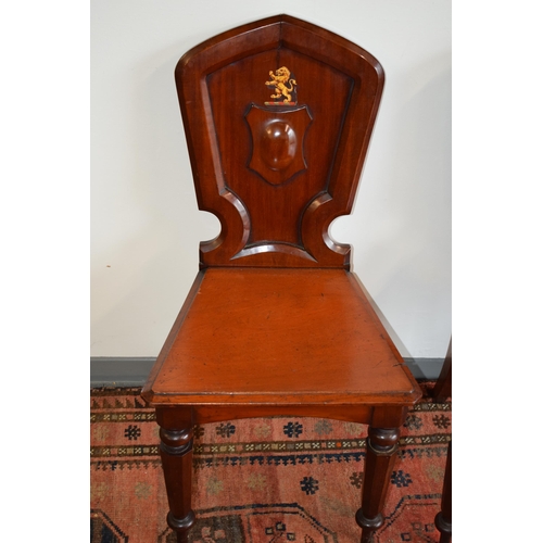 217 - A pair of antique mahogany hall chairs with lion emblem and shaped backs, 92cm tall (2).