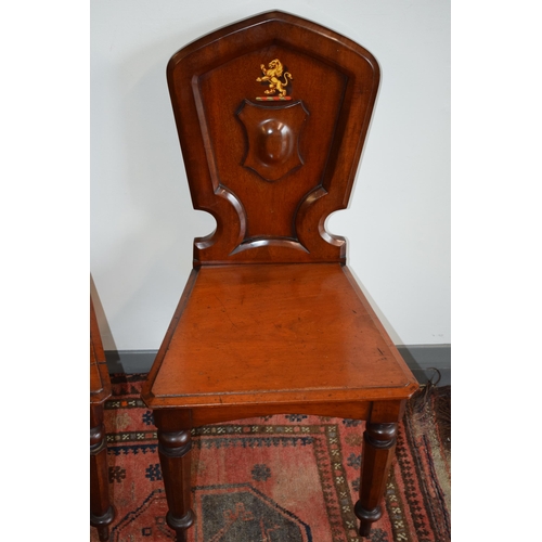 217 - A pair of antique mahogany hall chairs with lion emblem and shaped backs, 92cm tall (2).