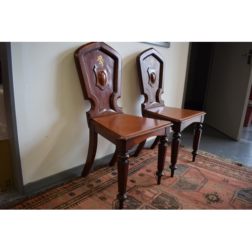 217 - A pair of antique mahogany hall chairs with lion emblem and shaped backs, 92cm tall (2).