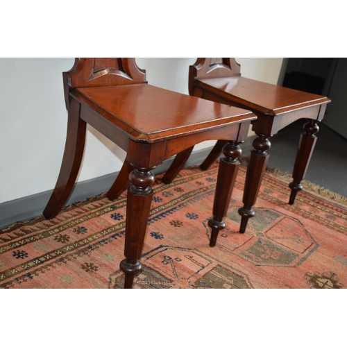 217 - A pair of antique mahogany hall chairs with lion emblem and shaped backs, 92cm tall (2).