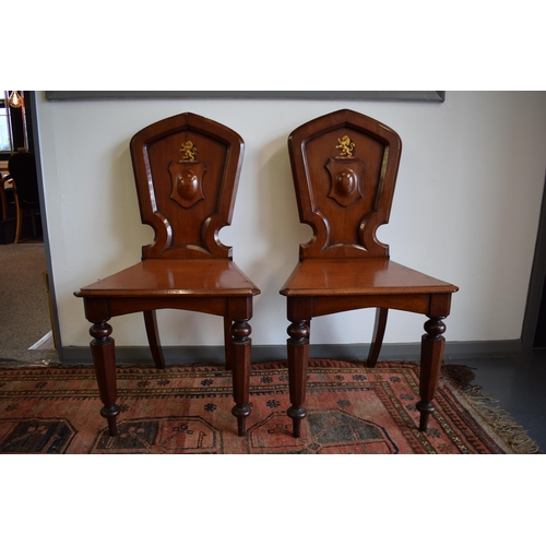 217 - A pair of antique mahogany hall chairs with lion emblem and shaped backs, 92cm tall (2).