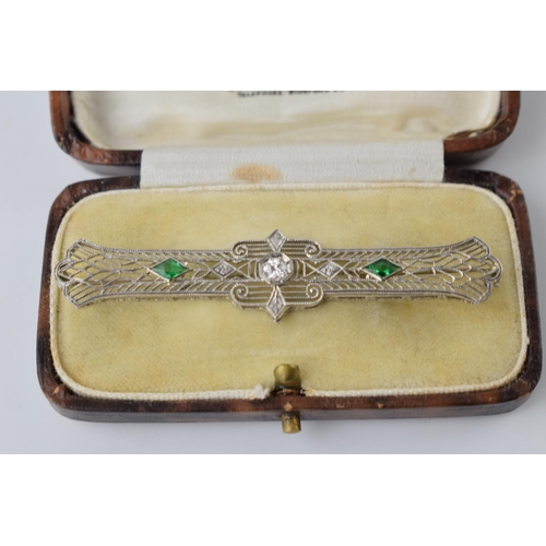 640 - 14ct white gold filigree brooch set with 0.2ct diamond and emeralds, 65mm wide, 3.8 grams, in origin... 