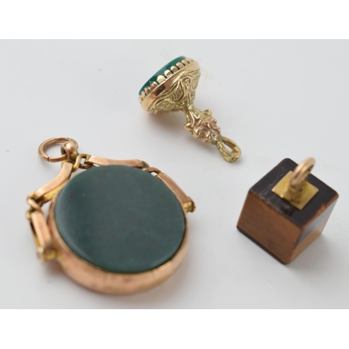 641 - A trio of 9ct gold fobs to include an agate swivel fob, a smaller fob and a 9ct gold mounted tigers ... 