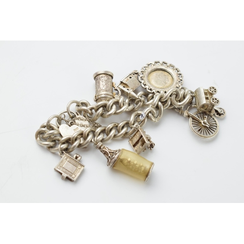 667 - Silver charm bracelet, 55.4 grams to include charms such as a Penny Farthing, a tankard, a church an... 