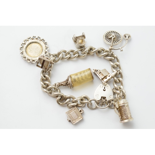 667 - Silver charm bracelet, 55.4 grams to include charms such as a Penny Farthing, a tankard, a church an... 