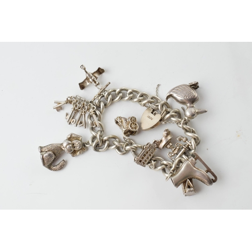 674 - Silver charm bracelet, 55.7 grams, to include an ice skating boot, a duck, keys and others.