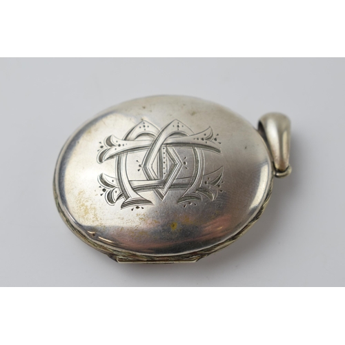 677 - Victorian silver locket (front and back) with birds in flight to front, containing images.